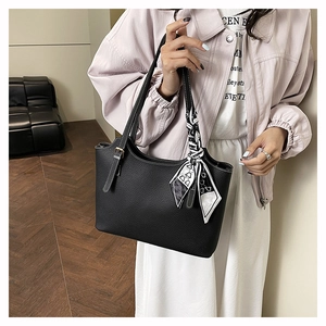 Detail of black pebbled leather tote bag with white contrast stitching and heart print scarf