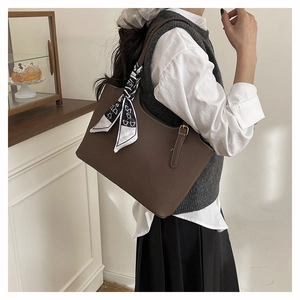 Detail of dark brown lychee leather tote bag with printed silk scarf on the handle