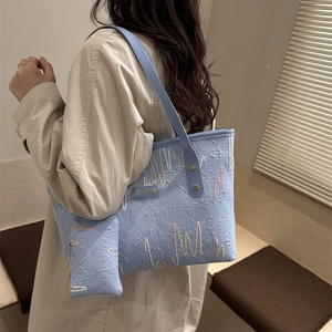 Light blue tote bag with 3D embossed texture and colorful embroidery on model