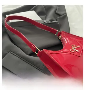 Dettaglio di una borsa in vernice rossa con un fiocco decorativo in metallo dorato