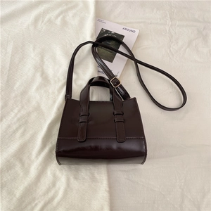 Detail view of glossy dark coffee square crossbody bag with decorative buckle straps