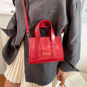 Detail of red synthetic leather mini square bag featuring gold FASHION & BAGS lettering