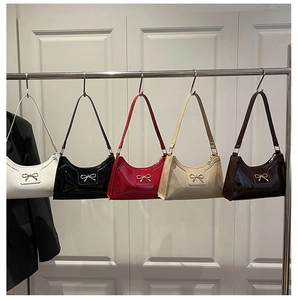 Detailed row of five patent leather underarm bags with metallic bow knots in various colors
