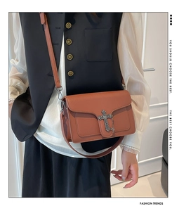 Detail of reddish brown leather crossbody bag with silver metal cross and chain