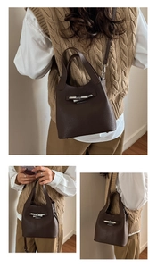 Detail view of brown lychee grain leather bucket bag with silver metal bar lock