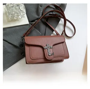 Detail view of brown leather crossbody bag with vintage gothic cross buckle and chain