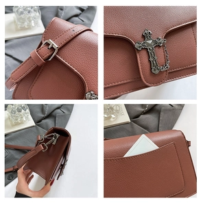 Detail of reddish brown lychee grain leather crossbody bag with silver gothic cross charm