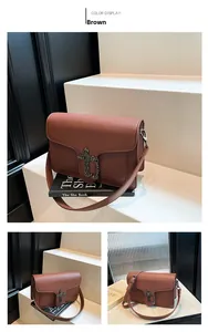 Detail of brown leather flap bag with vintage metal cross buckle and decorative chain