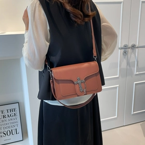 Fashionable terracotta crossbody bag with silver cross charm and chic metal chain strap
