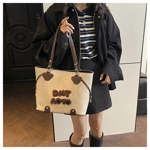 Dettaglio della borsa tote retrò che mostra la texture in pelle screpolata e la toppa in peluche