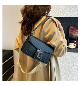 Detail view of black litchi pattern leather shoulder bag with vintage silver cross metal hardware
