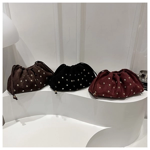 Close-up of studded drawstring bucket bags in brown, black, and burgundy suede finishes