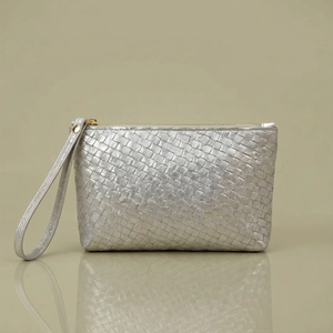 Detailed view of silver woven leather clutch with metallic finish and gold zipper closure