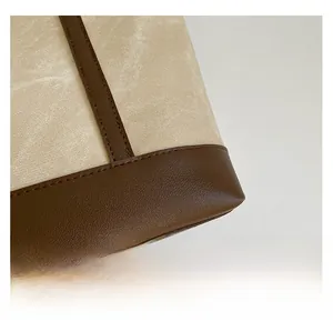Detail shot of heavy-duty cream canvas tote with premium brown leather reinforced base