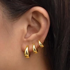 Dreiteiliges Set goldene Tropfenohrringe mit polierter Spiegeloberfläche am Model