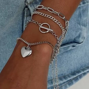Silver layered bracelet set with heart pendant and OT buckle on denim background