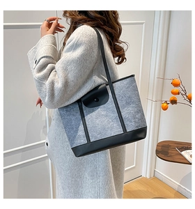 Gray felt tote bag with black leather accents shown worn by a model in a cozy interior