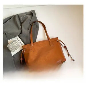 Detailed view of brown leather tote bag with embossed kitty pattern and drawstring detail