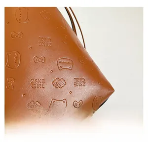 Detail of caramel leather tote featuring textured litchi grain and embossed patterns