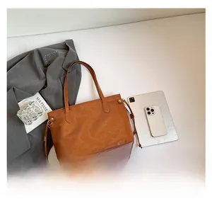 Macro detail of brown tote bag featuring embossed minimalist icons and leather drawstrings