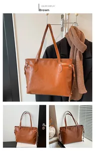 Detailed view of brown tote bag featuring embossed patterns and long shoulder strap details