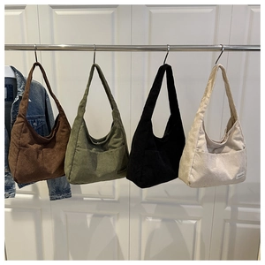 Detailed view of four corduroy tote bags in brown green black and cream with front pockets