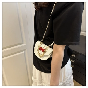 Detail view of white cherry crossbody bag with gold chunky chain and red 3D accents