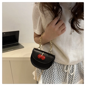 Side view of a mini black saddle bag with cherry rhinestone decor and gold chain strap
