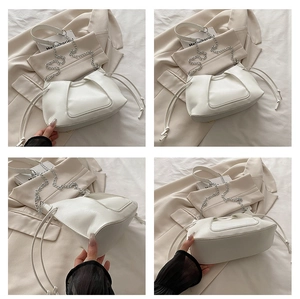 Detail view of a white ruched bucket bag with silver chain and drawstring adjustment