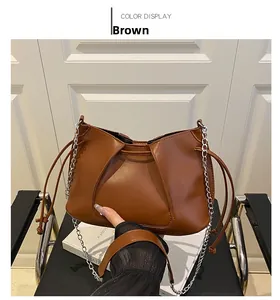 Detail of brown pleated handbag with silver chain and drawstring in minimalist style