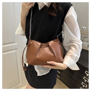 Detail shot of brown pleated leather shoulder bag with sleek silver chain strap