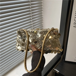 Dettaglio delle paillettes dorate scintillanti e del manico di una borsa alla moda