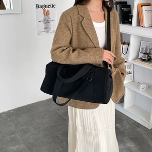 Minimalistische schwarze Nylon-Boston-Tasche als geräumige Umhängetasche an einem Model
