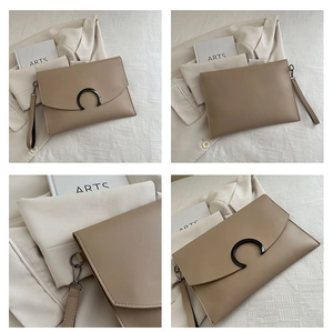 Detail view of khaki leather envelope clutch with minimalist C-shaped metal buckle and wristlet