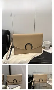 Detailed view of a khaki leather envelope clutch bag with a black C-shaped metal clasp