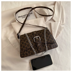 Détail d'un sac à bandoulière vintage à monogramme avec chaîne argentée et boucle