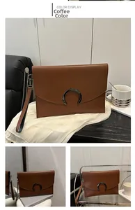 Macro detail of brown leather envelope clutch bag with crescent metal lock and wristlet