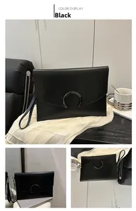 Detail of minimalist black leather envelope clutch with crescent metal clasp and wrist strap