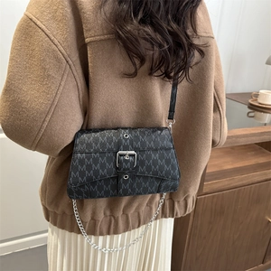 Chic black monogram chain square crossbody bag worn over a stylish brown wool coat
