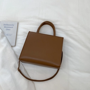 Detail shot of a vintage brown leather tote bag with dual handles and adjustable strap