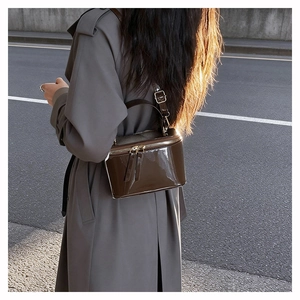 Detail of vintage brown patent leather box bag showing mirror-like shine and gold zipper