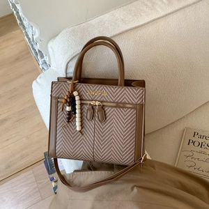 Detail of retro textured brown leather and herringbone weave crossbody bag on a white sofa