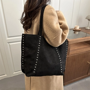 Grand sac cabas rétro en daim noir avec rivets porté sur un manteau de laine camel