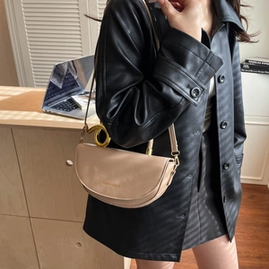 Minimalist beige saddle shoulder bag with gold ring handle and metal logo detail
