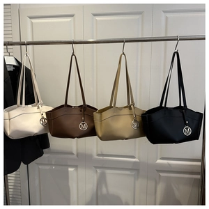 Detail view of large tote bags in four colors with circular metal M pendant and long handles