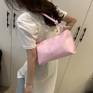 Pink faux leather shoulder bag with knot strap detail worn with white top and denim jeans