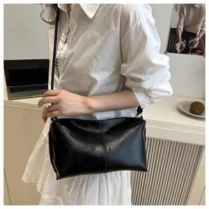 Minimalist black soft leather crossbody bag styled in a casual lifestyle setting