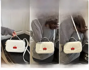Three-way carry demonstration of white crossbody square bag with red cherry charm