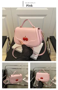Detail of pink shoulder bag with red 3D cherry decor and adjustable leather strap
