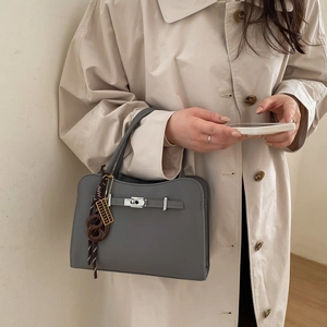 Grey textured leather tote bag with silver twist lock shown from a stylish side angle